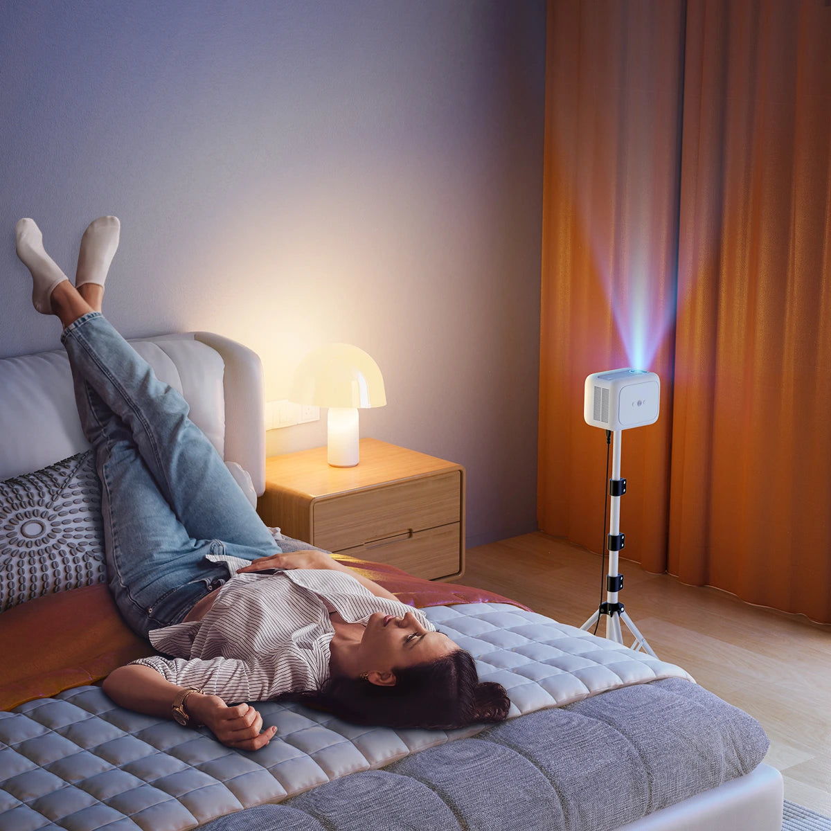 Woman lying on a bed with a Yaber projector on a stand casting light onto the wall.