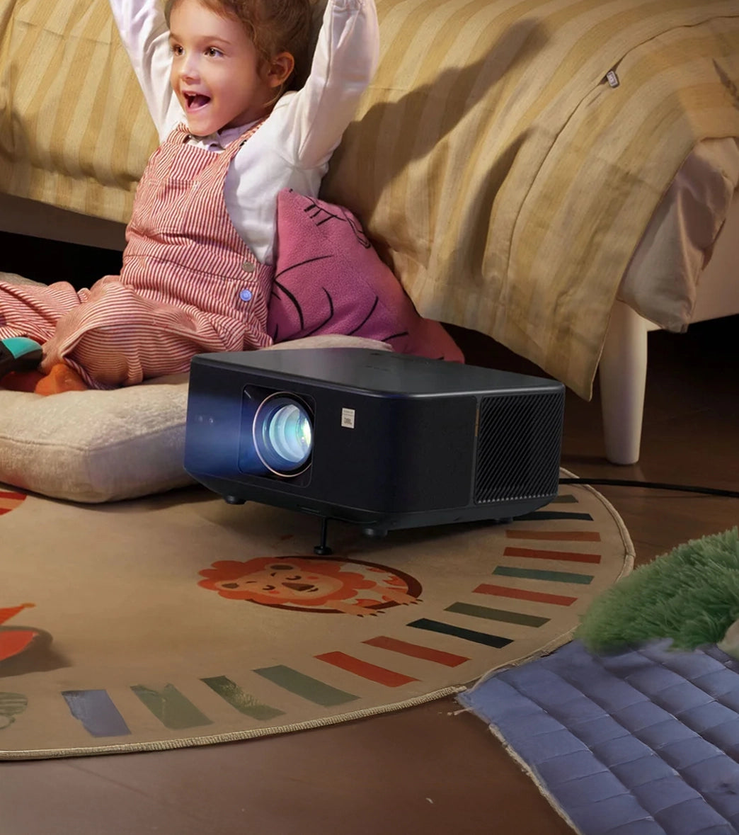 Child sitting on a bed with a yaber projector on the floor in a room.