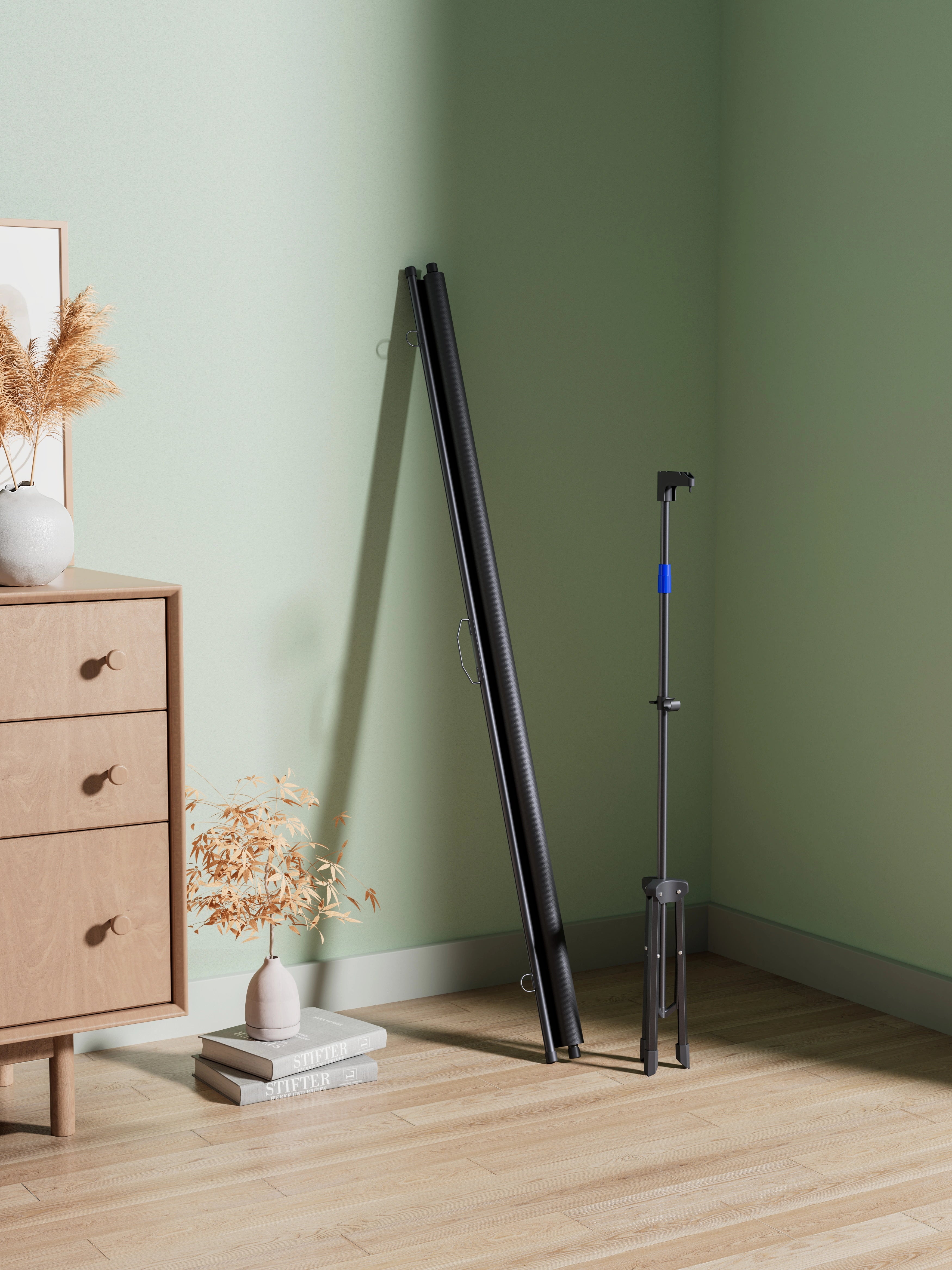 Leaning projector screen with stand against a green wall in a room with a wooden dresser and decor.