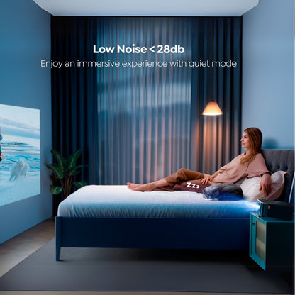 Woman relaxing on a bed in a bedroom with a projector screen displaying an ocean scene, featuring text about low noise levels.